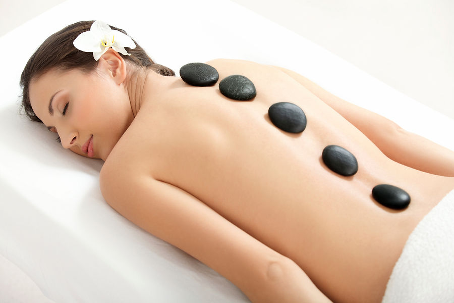 Woman relaxing on a massage table with warm hot stones on her back