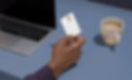 A picture of a man holding a credit card next to a laptop.