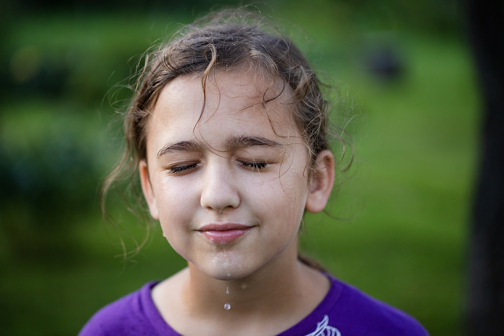 Young girl, face dripping with water in summer