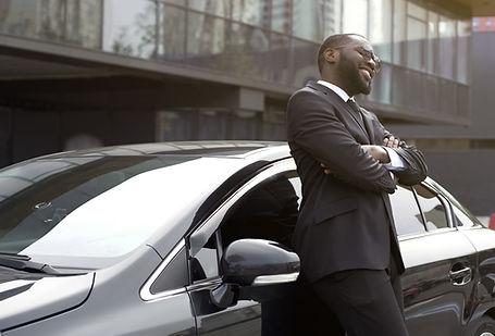 Chauffeur waiting outside of luxury black car