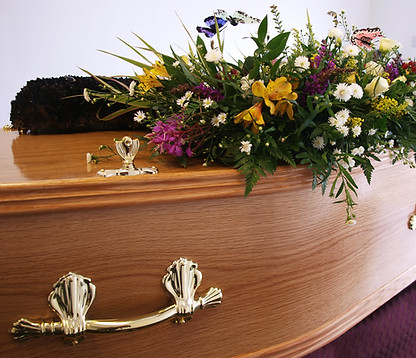 A coffin decorated with flowers awaits collection from the undertakers