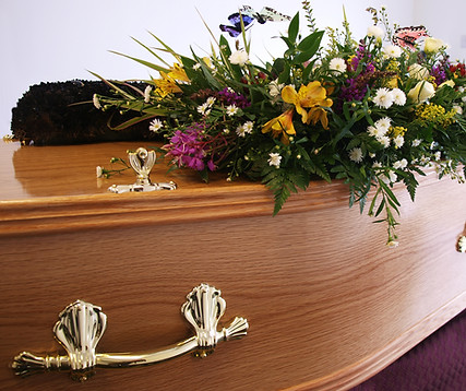 A coffin decorated with flowers awaits collection from the undertakers