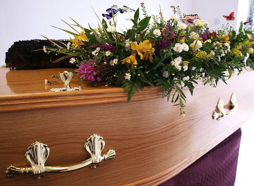 A coffin decorated with flowers awaits collection from the undertakers
