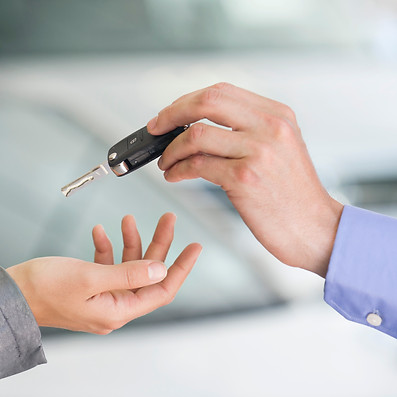 A close-up of two hands exchanging a car key.