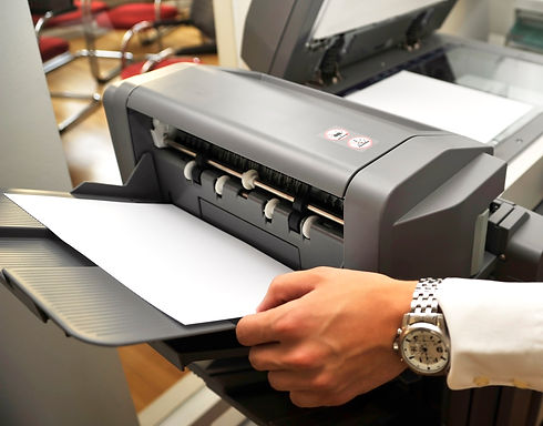 Hands retrieving printed paper from a desktop office photocopier tray