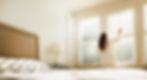 Woman in bathrobe opening bedroom window blinds