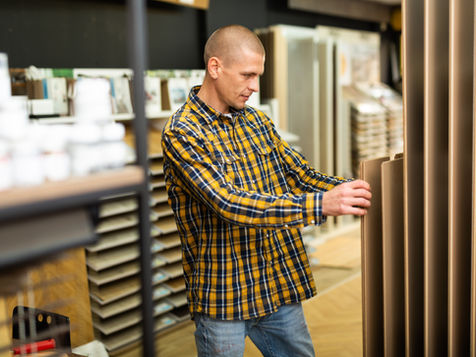 A man at a builders merchants looking at wood