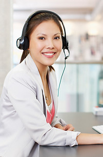 Portrait of confident businesswoman with headset at computer in office