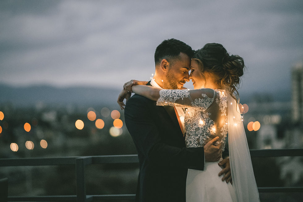 Newlywed couple embracing wrapped in warm fairy lights at twilight UK