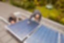 Technicians fitting solar photo voltaic panels to a house roof