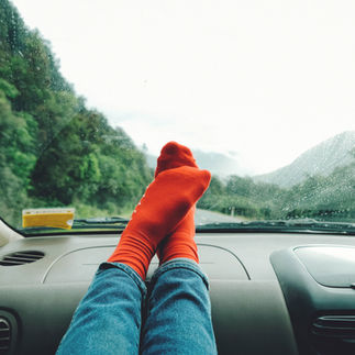 Feet in red socks on car dashboard with mountain view