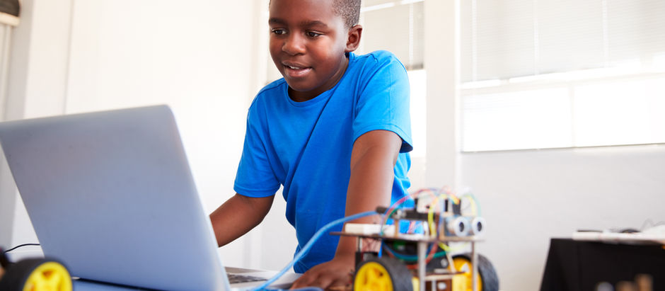 menino usando o computador para comandar o carrinho STEM