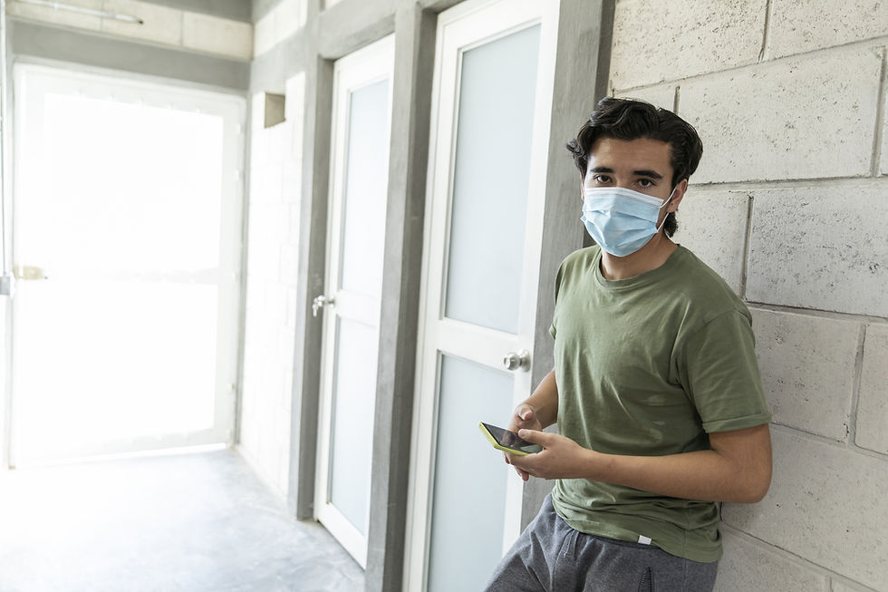 Person wearing mask leaning on the wall of office space