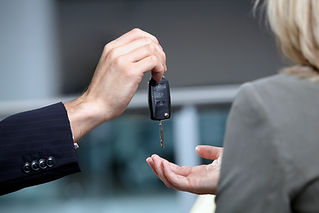 Salesman handing woman car keys in automobile showroom