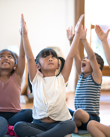 Kleine Kinder und ihre Lehrerin üben Yoga