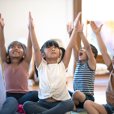 Little children and their teacher practicing yoga