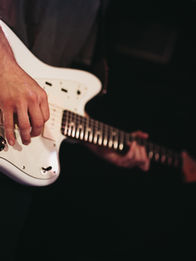 Student playing a white electric guitar.