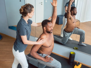 Professora ajudando seu aluno em um exercício postural de Pilates