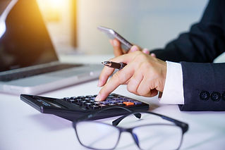 A Person using a calculator and holding a smartphone with eyeglasses