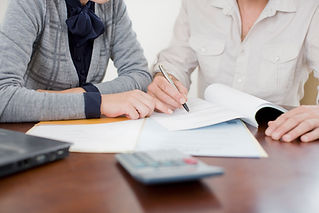 A person signing documents with another person pointing.