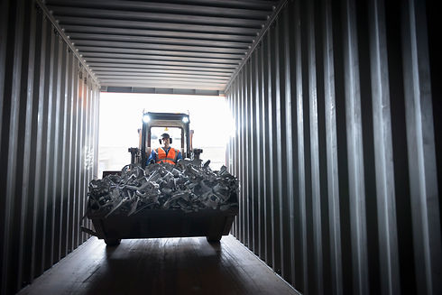 Digger filling shipping container with scrap metal