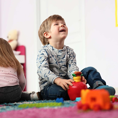 little boy laughing and playing with blocks