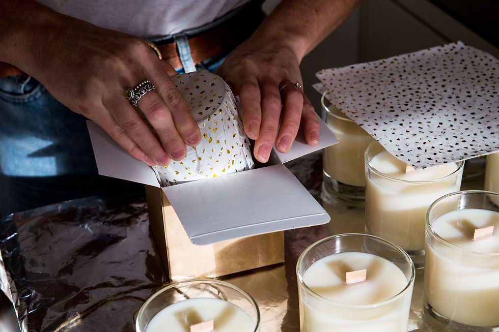 close-up image of a person's hand while wrapping handmade white jar candles