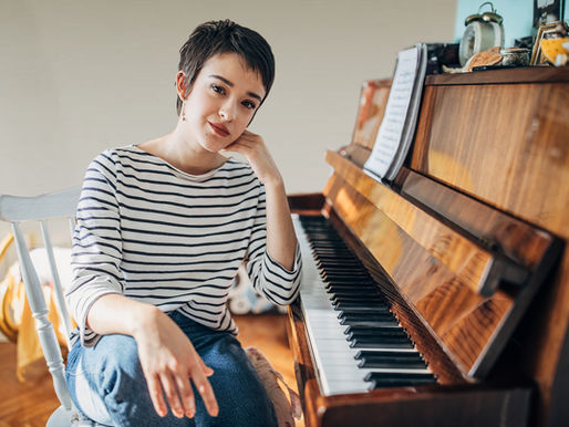 A person sitting by a piano with sheet music ready to write and compose.