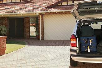 A car with its boot open, parked on a paved driveway