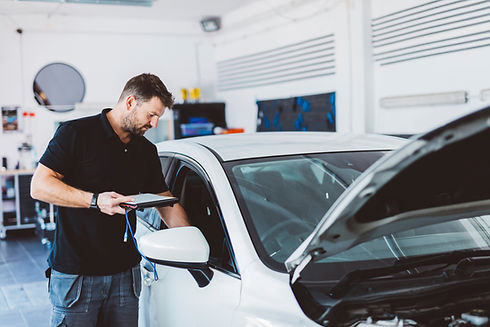 Mechanic holding device while examining car at auto repair shop