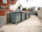 a row of black rubbish bins outside the house