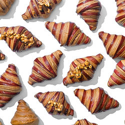 Artistic overhead shot of many delicious croissants on a white background.