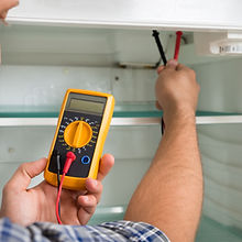 A technician checking the fridge with a digital multimeter