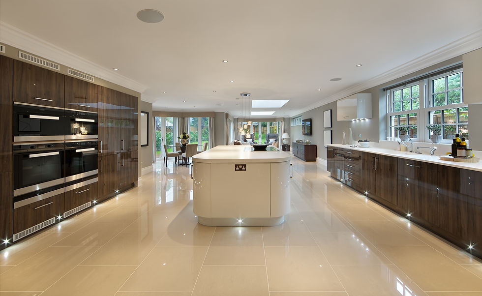 a large kitchen in a luxury new home with a large, curvy island in the centre and glossy w