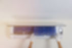 Man's hand is wearing a glove removing the air filter of the air conditioner for cleaning