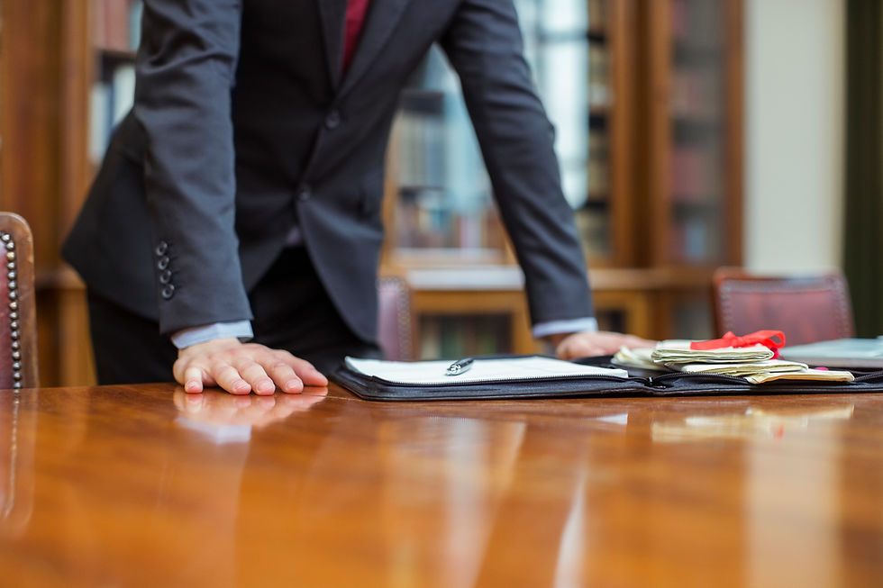 Professional man in dark suit leaning over wooden table with open folder and paperwork