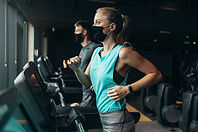 Woman wearing a face mask exercising on a treadmill inside a fitness centre