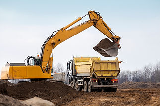 Digger loading trucks with soil