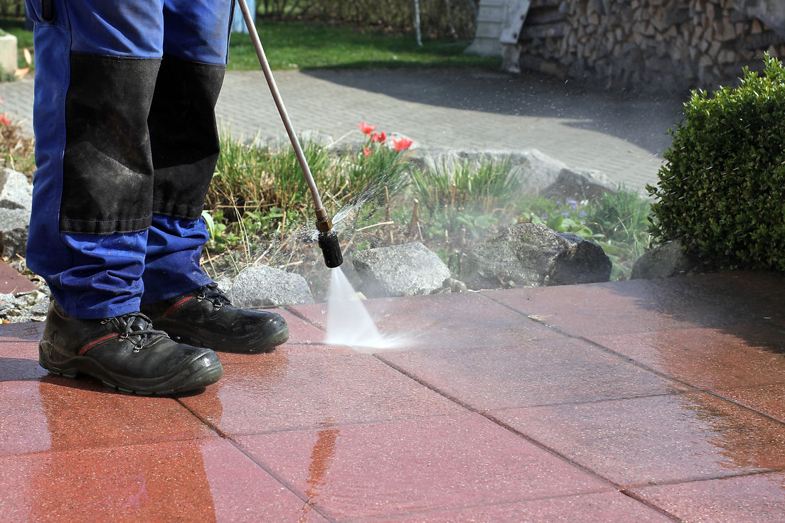 a worker cleaning patio using high-pressure jet washer