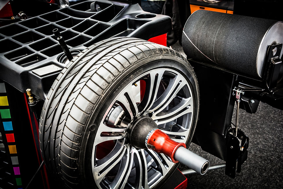 A modern alloy car wheel on the wheel balancing machine in an auto repair shop