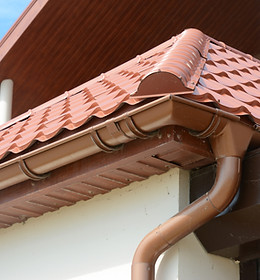 Close up on roof gutter holder and guttering downspout pipe with clay tiles