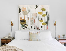 A serene bedroom sanctuary featuring white bedding and a soft light brown blanket, topped with a dash of green from the artwork above the bed, adding a touch of freshness and calm to the space.