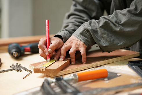 Carpenter using measuring tool and pencil