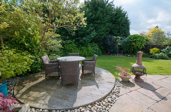 Garden patio with rattan table and chairs set on a green lawn