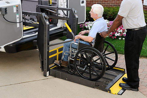 Carer assisting a senior man in a wheelchair on a car