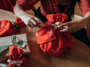 wrapping presents on a wood table in red wrapping paper