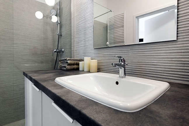 Modern white rectangular bathroom sink with chrome mixer tap set against a dark tiled background