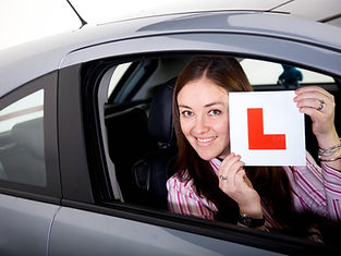 A woman holding learning sign inside a car