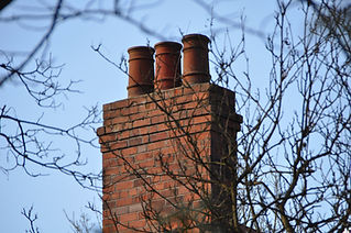 Low Angle View Of Brick Chimney Seen Through Branches