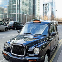 A classic black London taxi is parked on a city street